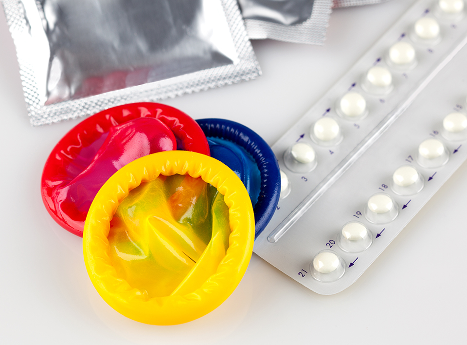 Photo of colorful condoms and oral birth control pills
